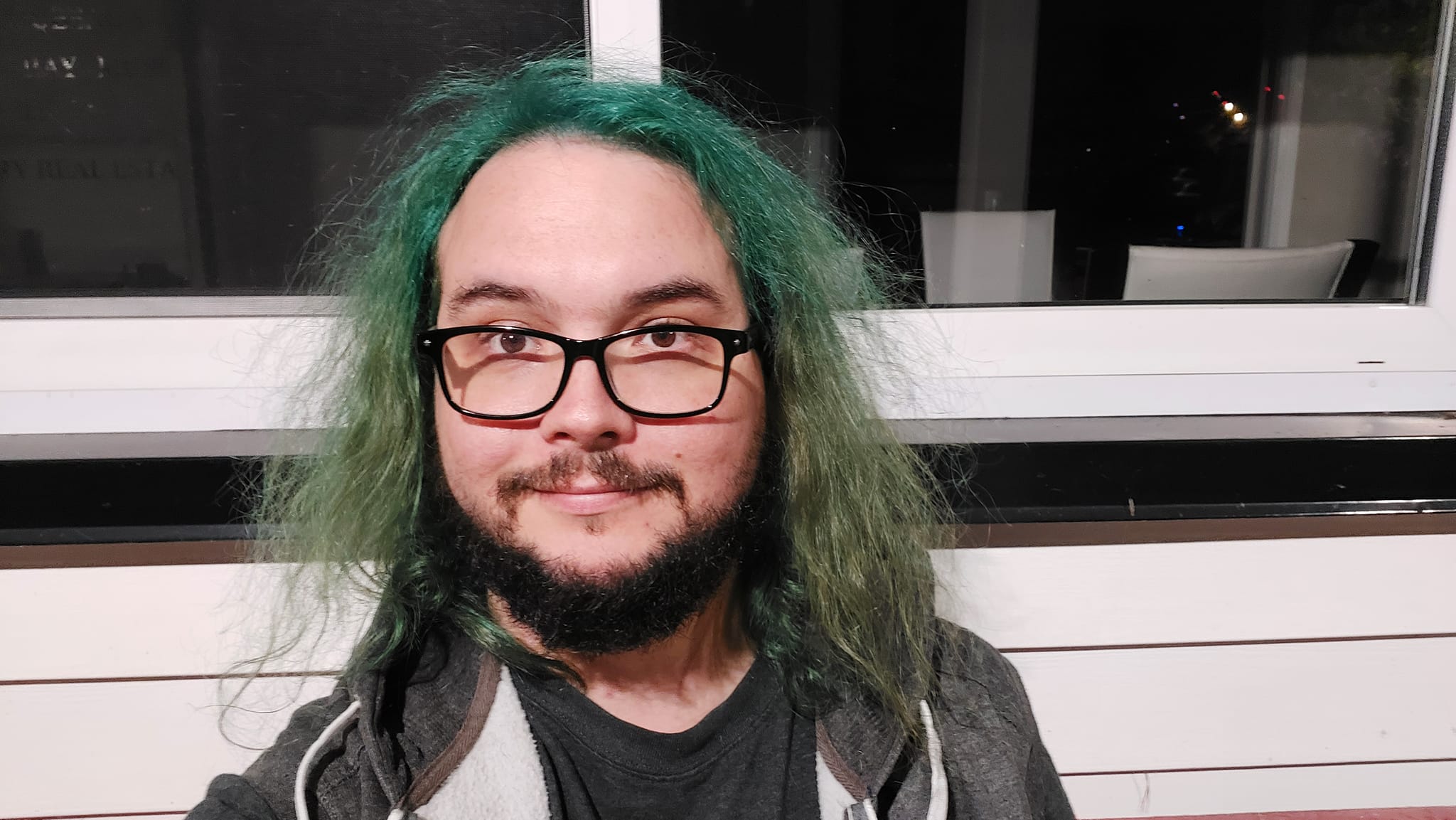 A man with green hair is outside after dark, Photo 5